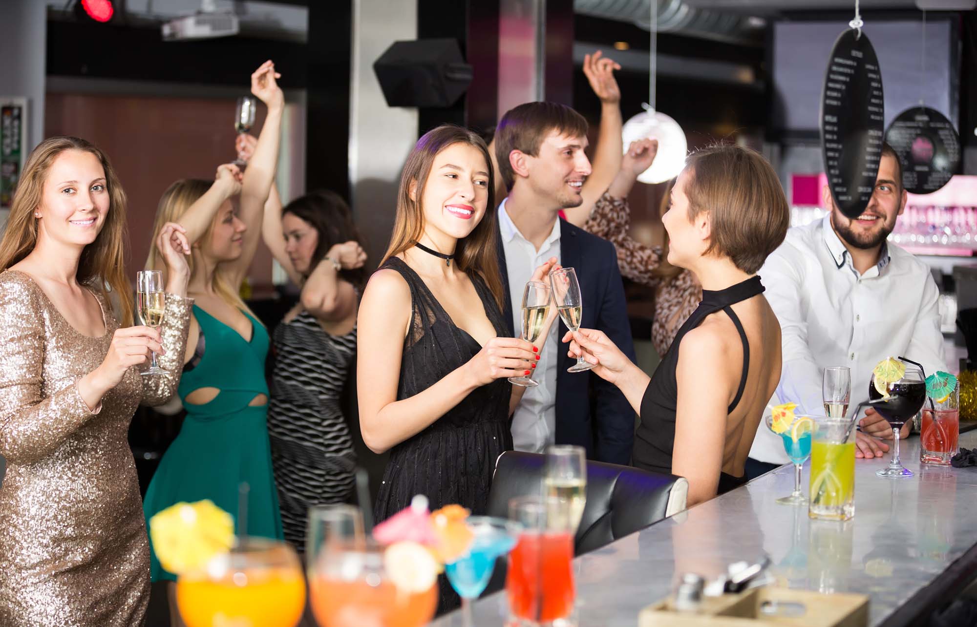 Happy colleagues dancing on corporate party with alcohol in hands